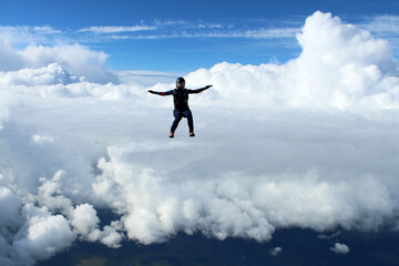 Fototapeta na wymiar Skydiving. A skydiver is flying above white clouds.