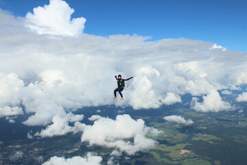 Fototapeta na wymiar Skydiving. A skydiver is flying above white clouds.