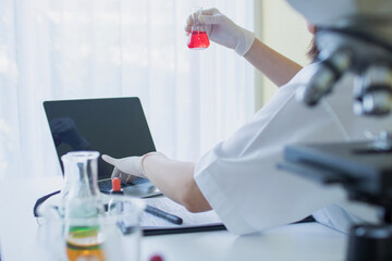 Laboratory Scientists in a Coverall Conducting Research. Chemist or doctor research and test Antiretroviral drugs  and find information on laptop , how to resolve coronavirus or covid 19