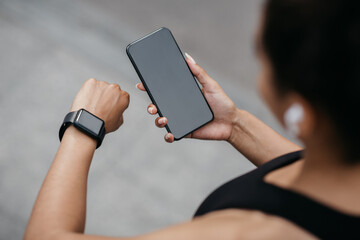 Device synchronization for sport. Girl in wireless headphones, looks at fitness tracker and...