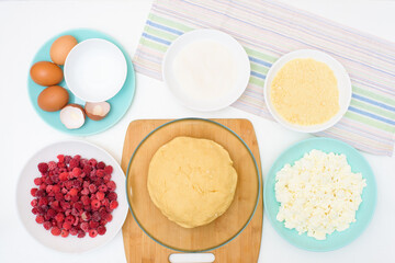 step by step cooking process and ingredients for homemade raspberry pie - egg, cottage cheese, flour, raspberries, sugar, dough, baking dish, butter. top view on a light background
