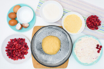 step by step cooking process and ingredients for homemade raspberry pie-egg, cottage cheese, flour, raspberries, sugar, dough, baking dish, butter. top view on a light background. mixing ingredients