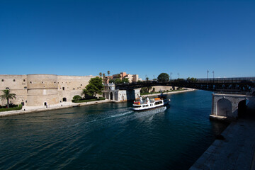 small boat that cross the swing bridge in front of the aragonian castle in taranto on blue sky...