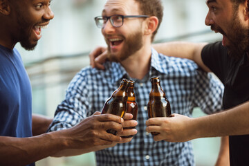 Group of happy friends having beer party in summer day. Resting together outdoor, celebrating and relaxing, laughting. Summer lifestyle, friendship concept. Clinking beer's bottles, look cheerful