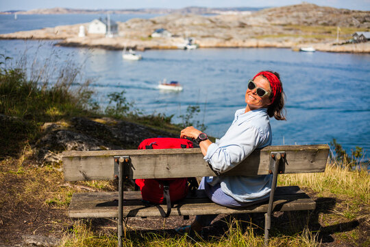 A portrait of a young woman sitting on a bench and enjoying the views on the Swedish west coast, Sweden