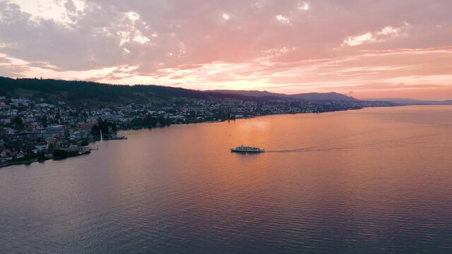 Drone flight over ferry crossing the lake of Zurich during a beautiful summer sunset in Switzerland