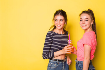 Happy young cheerful cucasina beauty girls together smiling with cocktail on yellow background