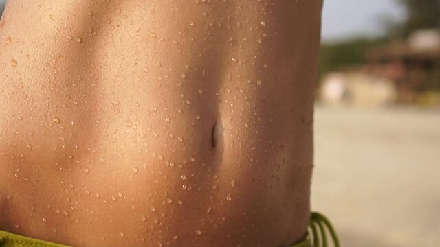 Water drops on wet skin of a beautiful sexy woman on the beach on a hot day.