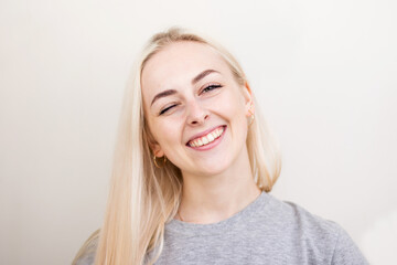 Pretty smiling joyfully female with fair hair, dressed casually, looking with satisfaction at camera, being happy. Studio shot of good-looking beautiful woman