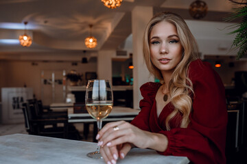 woman with glass of white wine in cafe or restaurant. sexy young blonde girl
