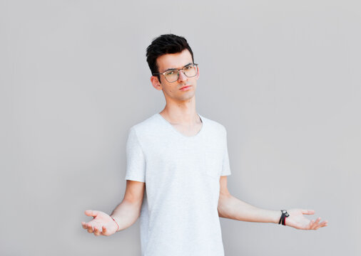 Closeup portrait of dumb clueless young man, arms out asking what's the problem who cares so what, I don't know. Isolated on white background. Negative human emotion, facial expressions, attitude