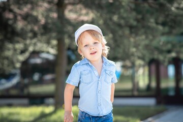 A boy in a white cap runs through the Park and smiles.