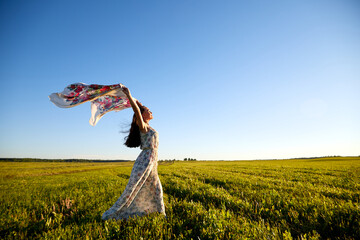 Beautiful woman or girl with magnificent figure and plastic movements walking and dancing in green field with trimmed grass in the setting sun during sunset with warm yellow light. © keleny