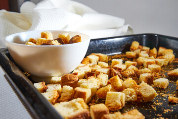 Square toasted pieces of homemade delicious rusk, hardtack, Dryasdust, zwieback on a white plate and baking sheet.