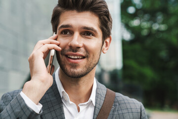 Cheerful business man outdoors talking by mobile phone