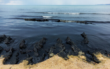 The sea and the beach are polluted with oil. A crude oil spill on the sand of a city beach. Beach...