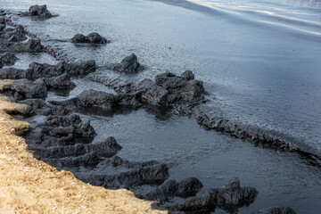 The sea and the beach are polluted with oil. A crude oil spill on the sand of a city beach. Beach...
