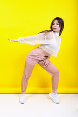 A beautiful girl in sportswear poses on a yellow background. Fashion shooting of sportswear