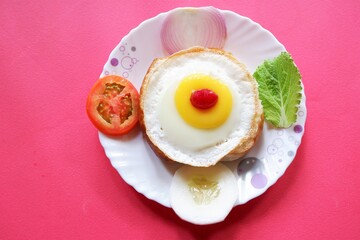 Homemade burger bun with fried egg and  fresh vegetables on a white plate . Top view image.