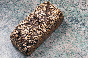 a rectangular loaf of wheat bread with cereal sprinkles on the kitchen table