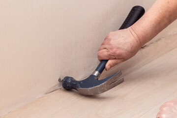 Closeup hand with nail and hammer at wall.