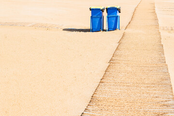 Garbage cans besides boardwalk on beach