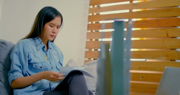 Slow motion short, Young Asian woman get debt of credit card, Thai womansitting on sofa, looking and worry about bill paper, no money to pay and have problem, because shopping online and no working
