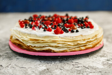 Sweet homemade pancakes with berries on a pink plate on a gray background.