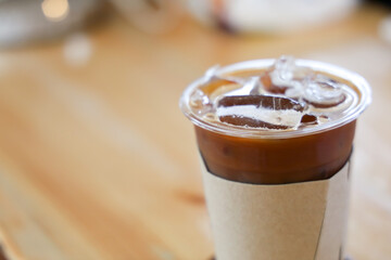 Mocha in plastic glass with paper cover for hand holding on wooden table background. Copy space for relax time,vacation,traveling,cafe and beverage concepts.