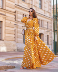 Pretty stylish woman wearing yellow and white polka-dot sundress and sunglasses. Beautiful girl in...