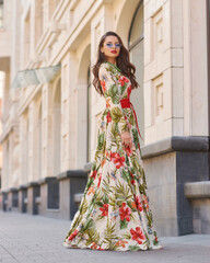 Fashion outdoor portrait. Elegant woman in colorful white red and green dress with floral design...