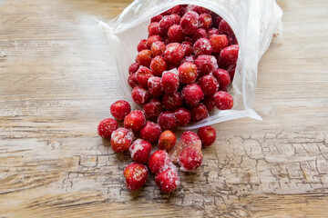 Frozen cherries in an open plastic bag from slightly above on wooden table