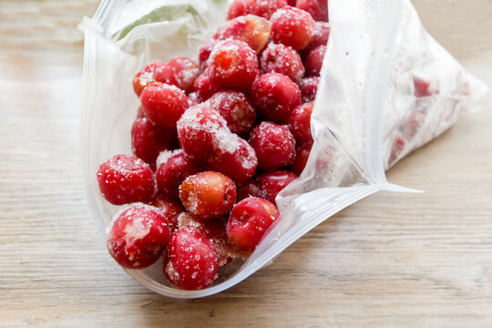 Frozen Cherries In An Open Plastic Bag In Low Angle On Wooden Table