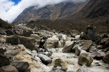 Mountain river and waterfall flowing through the rocks in Annapurna Massif valley on the Nepal ABC trek
