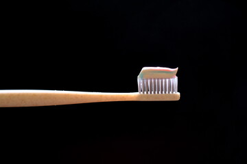 peach-colored toothpaste on toothbrush on black background