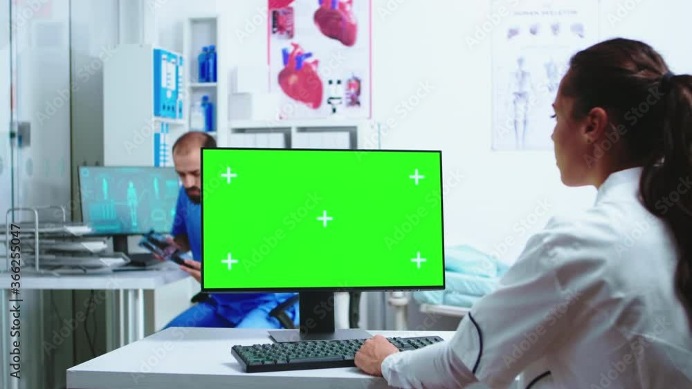 Aufkleber assistant giving doctor patient x-ray while she is working on computer with copy space green screen 