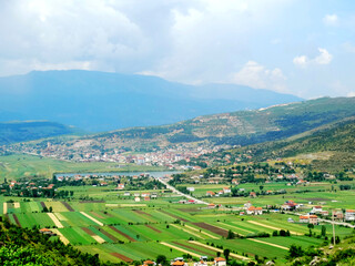 Natural countryside landscape with agricultural crops in valley field beside mountains. Transportation way from Macedonia to Albania.