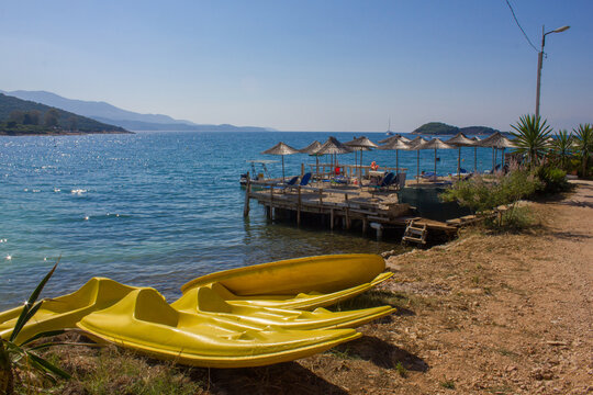  Kayak boats drying on the shore near empty Ksamil beach with sun beds and umbrellas during coronavirus social distancing restrictions