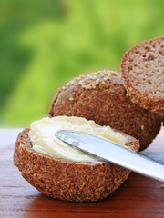 Spreading butter on crusty ketogenic almond flour bread, vertical.