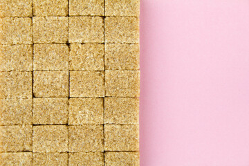 Brown sugar cubes on pink paper background. Copy space for text.