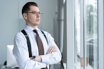 Portrait Of Businessman Standing By Window In Office