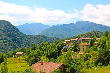 fondo paisaje con panorámica de un pequeño pueblo entre valles y montañas en verano