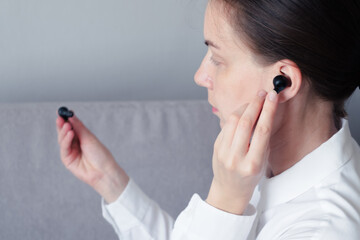 girl puts on wireless headphones.new technologies.isolated on gray background