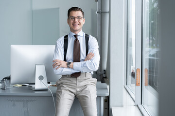 Naklejka na ściany i meble Portrait of a confident young businessman standing alone in a large modern office near his workplace