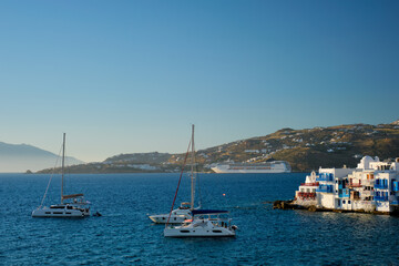 Fototapeta na wymiar Sunset in Mykonos island, Greece with yachts in the harbor and colorful waterfront houses of Little Venice romantic spot on sunset and cruise ship. Mykonos townd, Greece