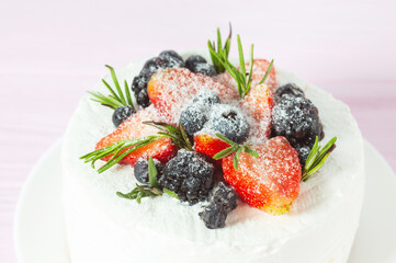 Cake with strawberries and blueberries  on the pink wooden background