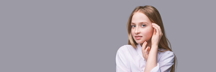 Fototapeta premium Beauty girl portrait. Young woman. Hand near nead. Face massage concept. White shirt. Cosmetology facelift laser. Medical rejuvenation scrub. Skin care hygiene. Grey background. Horizontal banner