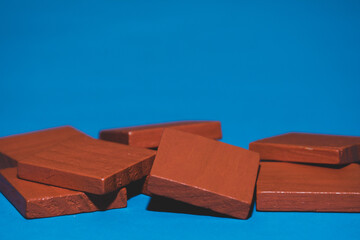 Bright colored orange tangram child geometric shape puzzle pieces  in a pile close up on blue background with copy space.