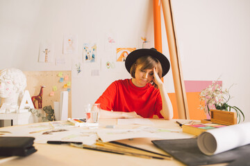 Sad girl Illustrator artist clutched head sitting at table in studio. State of apathy, frustration...