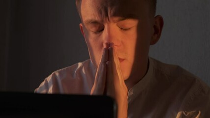 Businessman praying at office looking at laptop screen